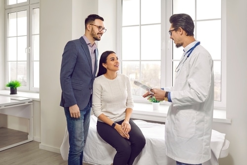man and woman talking with their doctor and planning pregnancy in a medical clinic