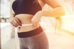 Woman measuring her waist to track her weight loss journey
